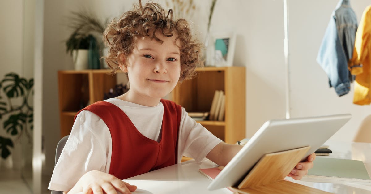 A young boy sitting at a table using a laptop